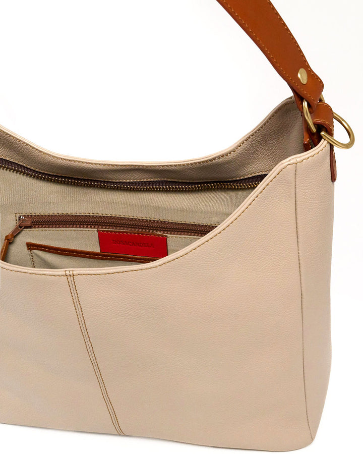 Close-up of a beige pebbled leather shoulder bag with a brown leather strap, gold-tone hardware, and an open zippered interior pocket.